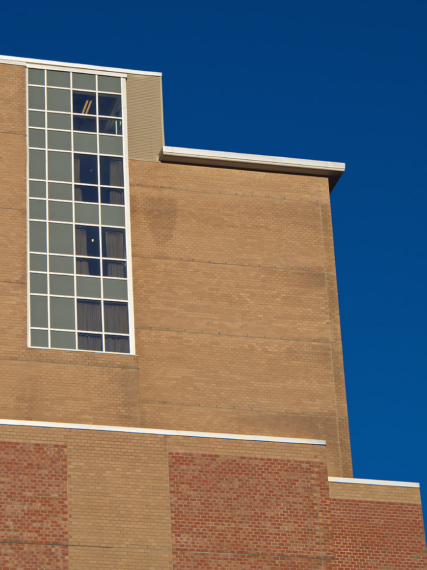 Modern Brick Building Facade with Large Window Against Blue Sky