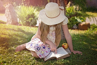 Girl in Straw Hat Reading Book in Garden