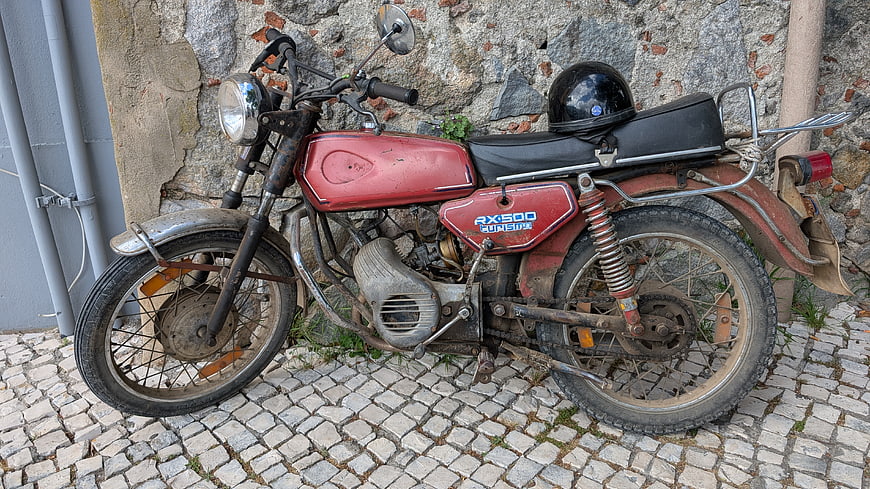 Vintage red motorcycle parked on cobblestone street