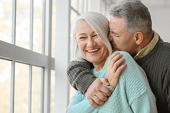 Happy Senior Couple Embracing by Window