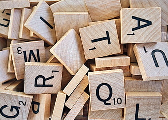 Scattered wooden Scrabble tiles with letters and numbers