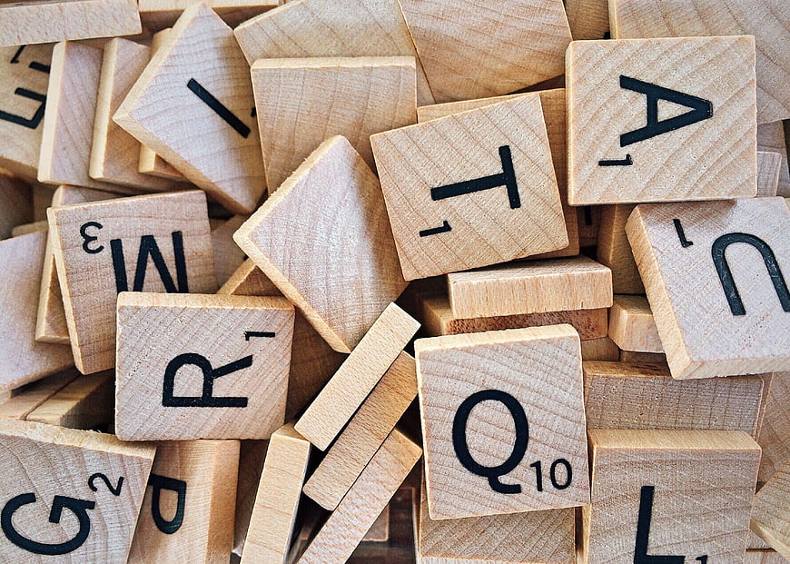 Scattered wooden Scrabble tiles with letters and numbers