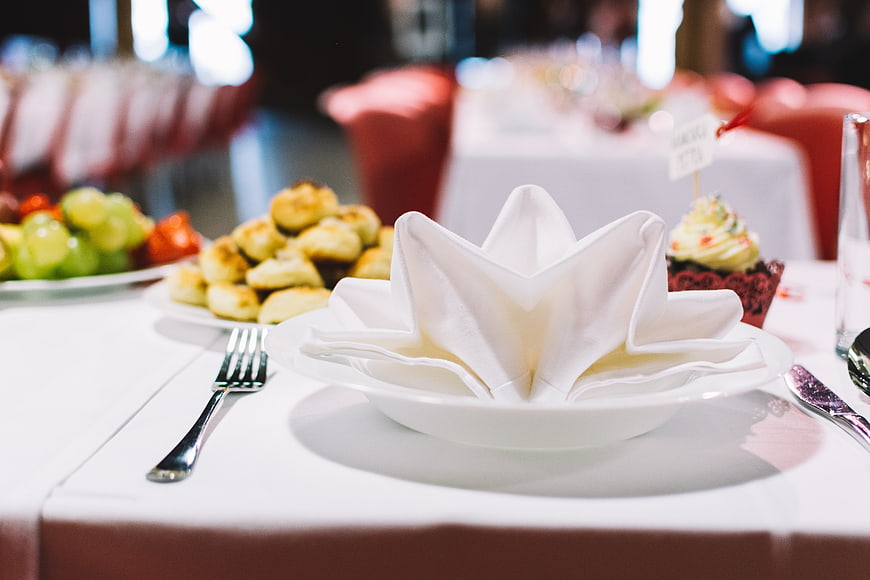Elegant white napkin fold on wedding reception table setting