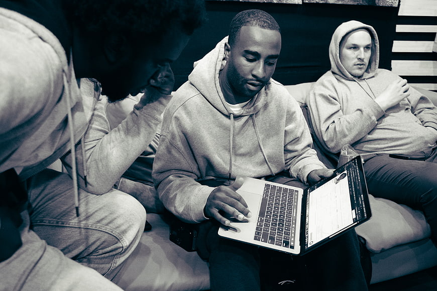 Three men collaborating on laptop in casual setting