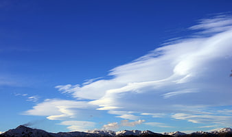 Snowy Mountain Range Under Blue Sky with Wispy Clouds