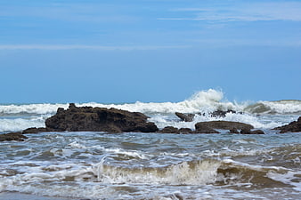Rough ocean waves crashing against dark coastal rocks