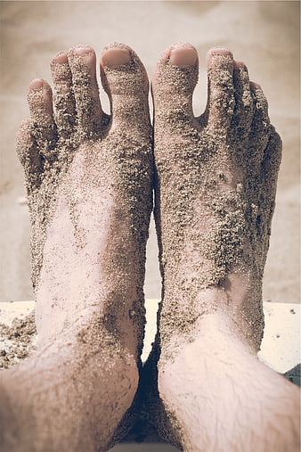 Close-up of bare feet covered in sand on a beach