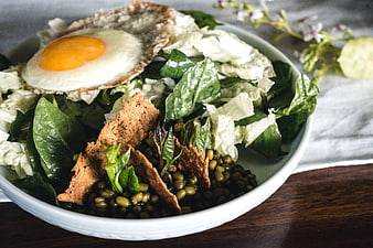 Healthy vegetarian salad bowl with fried egg and lentils