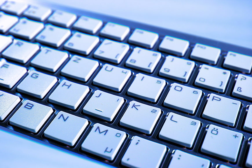 Close-up of white computer keyboard keys with blue lighting