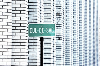 Green Cul-de-sac street sign against white brick wall