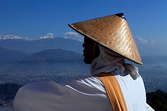 Man in Traditional Hat Viewing Mountain Landscape