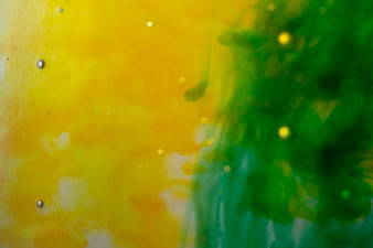 Abstract green and yellow ink swirling in water background