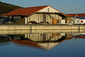 Industrial warehouse reflected in calm water with cyclist