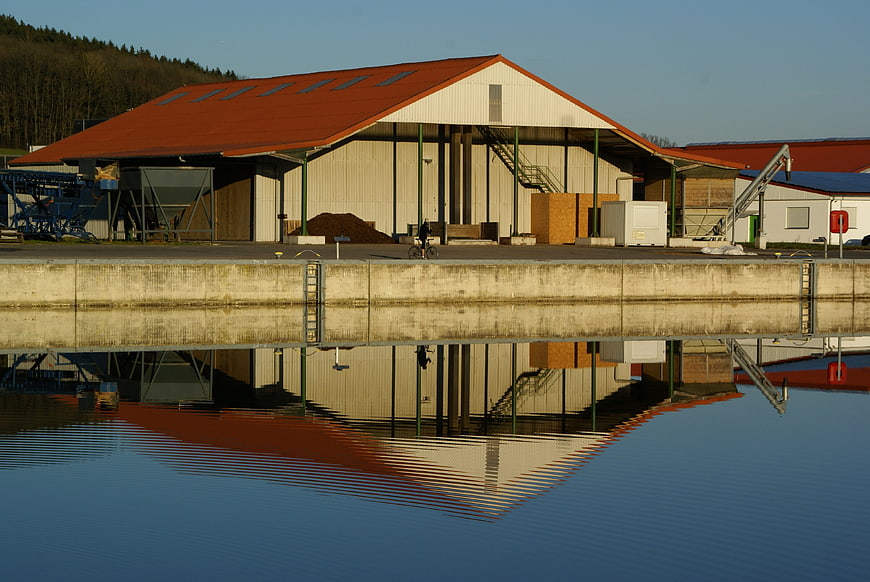Industrial warehouse reflected in calm water with cyclist