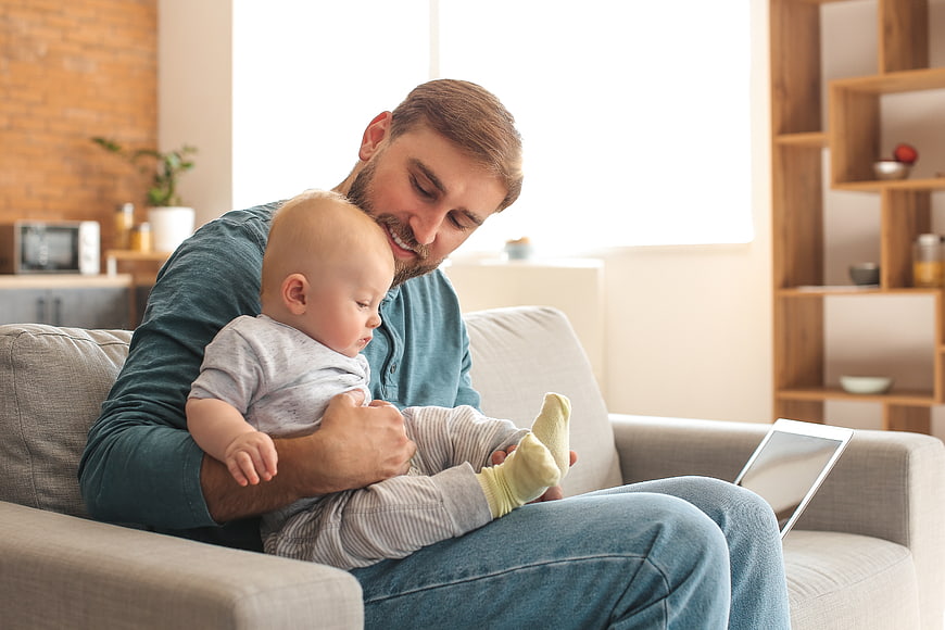 Happy Father Holding Baby on Sofa at Home