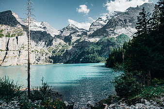 Turquoise Alpine Lake Surrounded by Snowy Mountains and Forest
