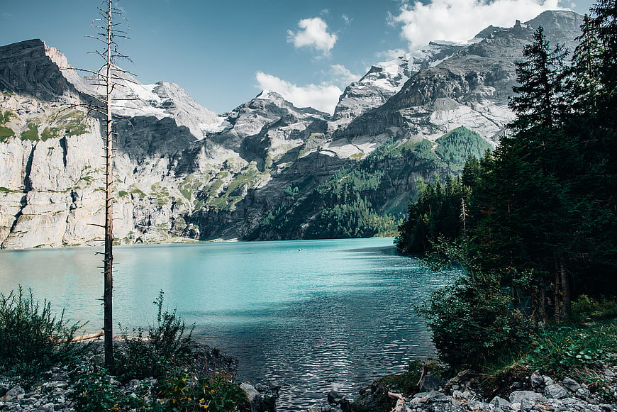 Turquoise Alpine Lake Surrounded by Snowy Mountains and Forest