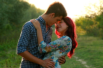 Romantic couple embracing in a sunlit field at golden hour