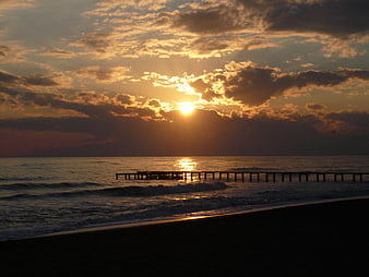 Dramatic Sunset Over Ocean With Silhouetted Pier