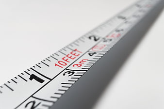 Close-up of white steel tape measure showing 10 feet and 3 meters