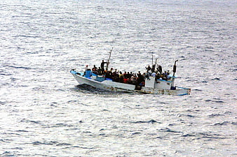 Overcrowded refugee boat on open sea