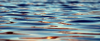 Abstract blue water ripples with golden sunset reflections