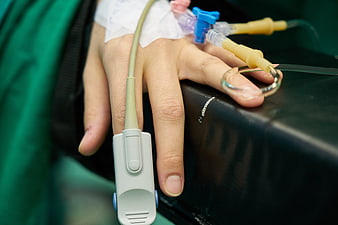 Close-up of patient hand with IV drip and pulse oximeter in hospital