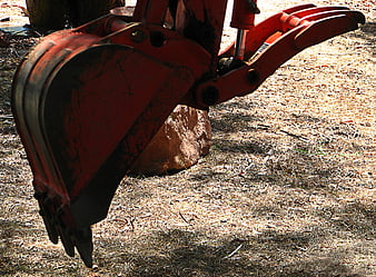 Close-up of red excavator bucket on construction site