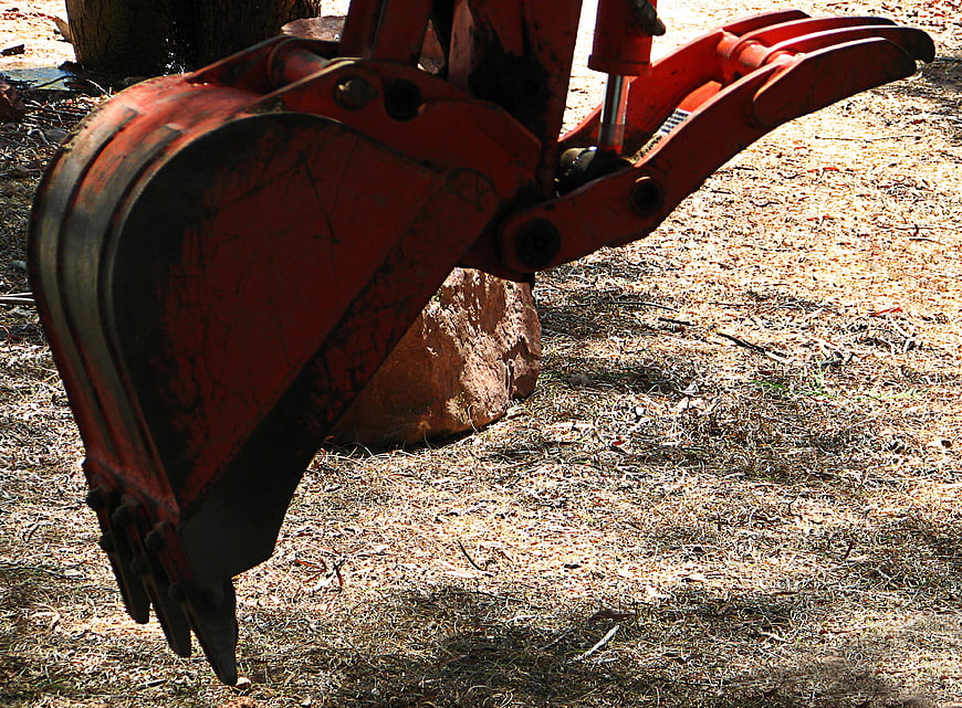 Close-up of red excavator bucket on construction site