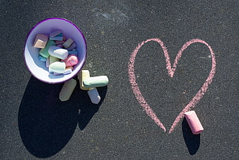 Pastel chalk heart drawn on asphalt with colorful chalk pieces