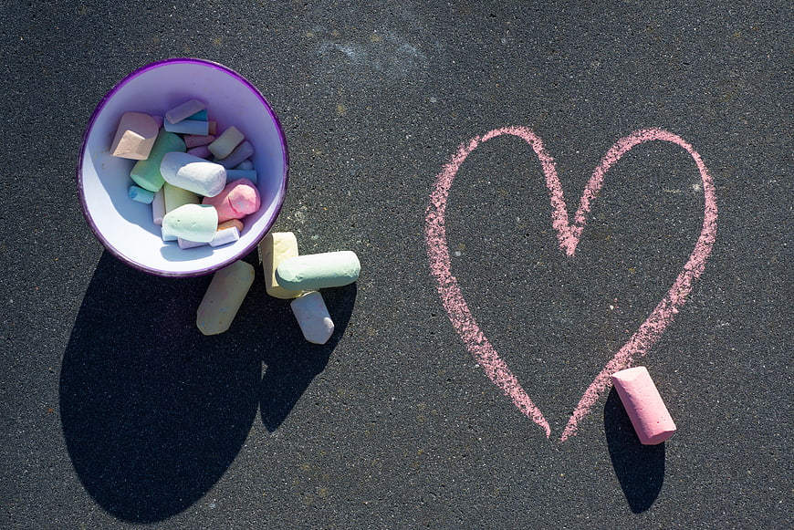 Pastel chalk heart drawn on asphalt with colorful chalk pieces