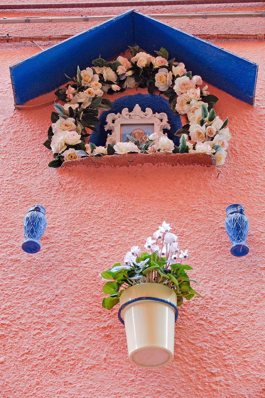Colorful Italian religious shrine with flowers and blue accents