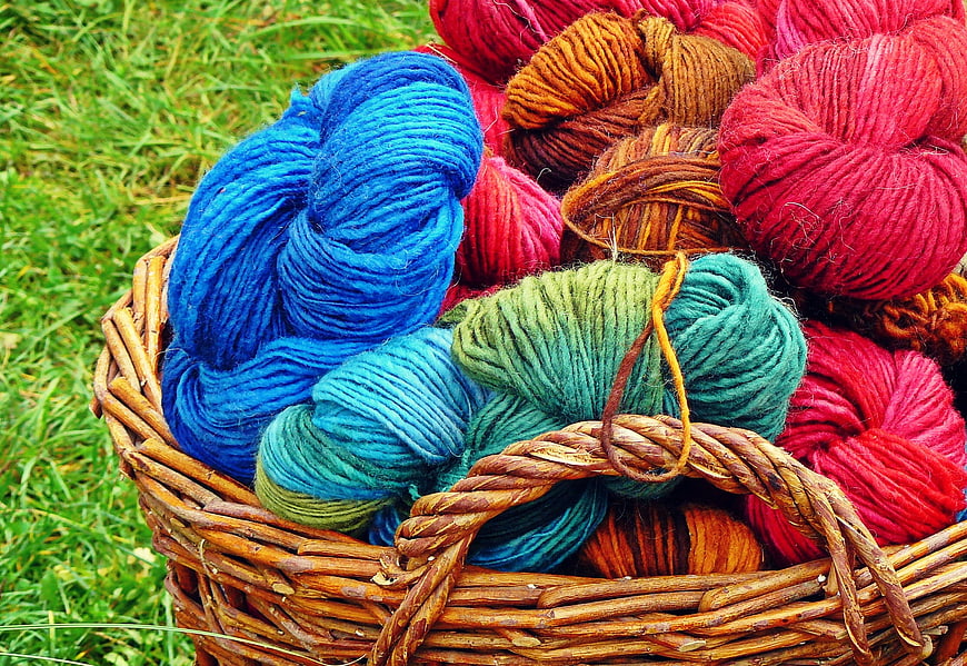 Colorful Hand-Spun Wool Skeins in Wicker Basket on Grass