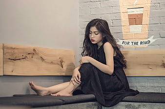 Sad young woman sitting alone on bench in cafe