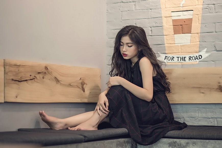 Sad young woman sitting alone on bench in cafe