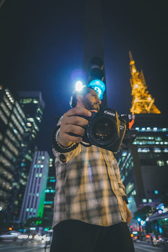 Man holding Canon camera in Tokyo at night