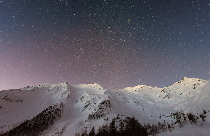 Snowy Mountain Peaks Under Starry Night Sky