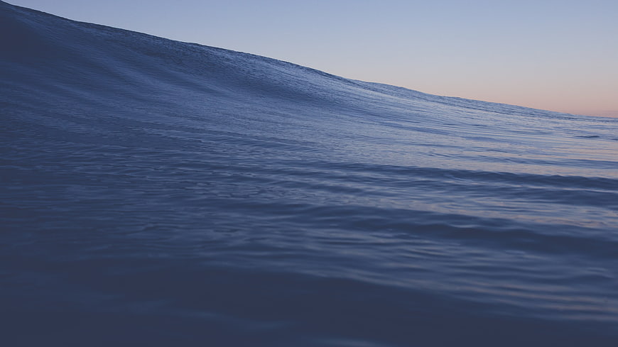 Serene Blue Ocean Wave at Dusk with Soft Horizon