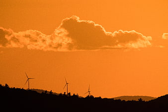 Silhouetted Wind Turbines Against Vibrant Orange Sunset Sky