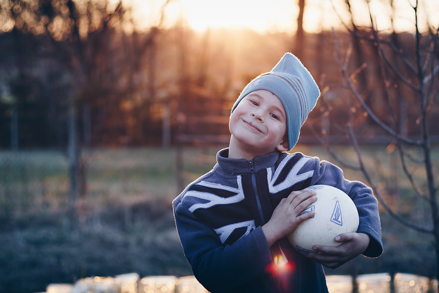Happy Boy Holding Soccer Ball at Sunset