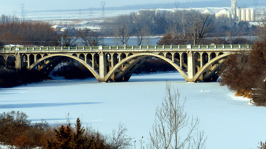 Concrete arch bridge over frozen river in winter landscape