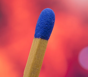 Macro shot of a blue matchstick head against a vibrant red background