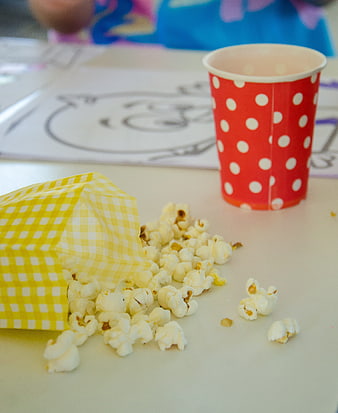 Spilled popcorn and red polka dot cup on table