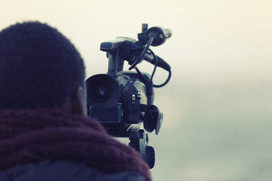 Videographer Filming with Professional Camera on Tripod