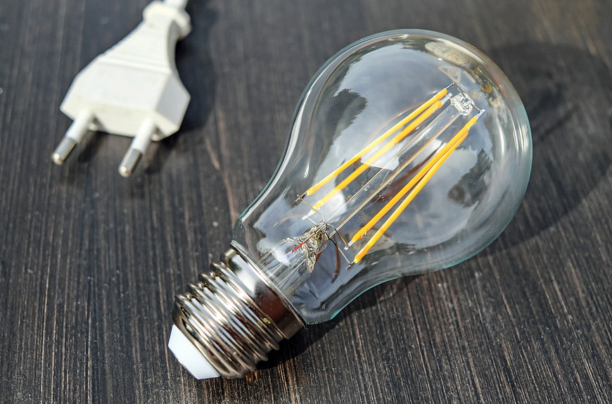 Modern LED filament bulb on dark wood with power plug