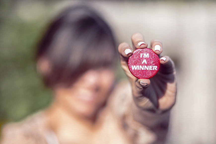 Woman holding red I'm a winner button close up
