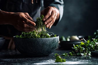 Chef Hands Plating Fresh Microgreens in Stone Bowl