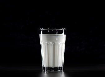 Glass of fresh milk on black background