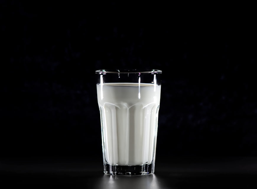 Glass of fresh milk on black background