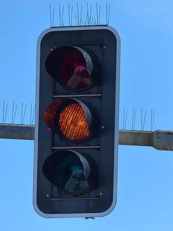 Close-up of traffic light with yellow signal illuminated against blue sky